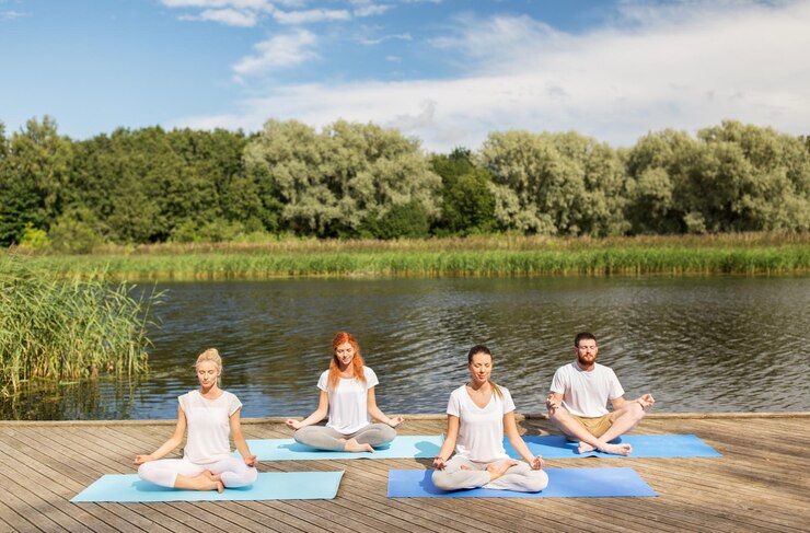 Foto fitness, sport, yoga en gezonde levensstijl concept - groep mensen mediteren in lotushouding op rivier- of meerligplaats