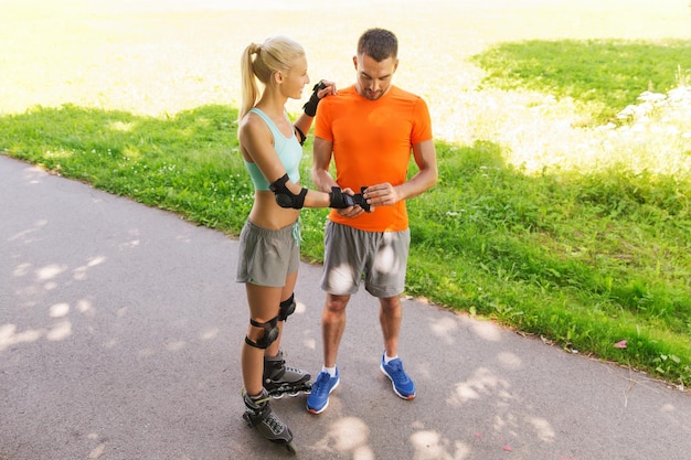 fitness, sport, zomer en gezond levensstijlconcept - gelukkig paar met rolschaatsen die buiten rijden