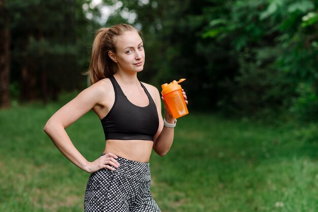 Fitness sportieve vrouw in sportkleding met fles water na trainingen in het park