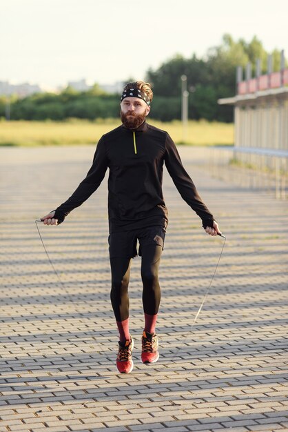 Uomo di sport di forma fisica che salta con la corda per saltare all'aperto