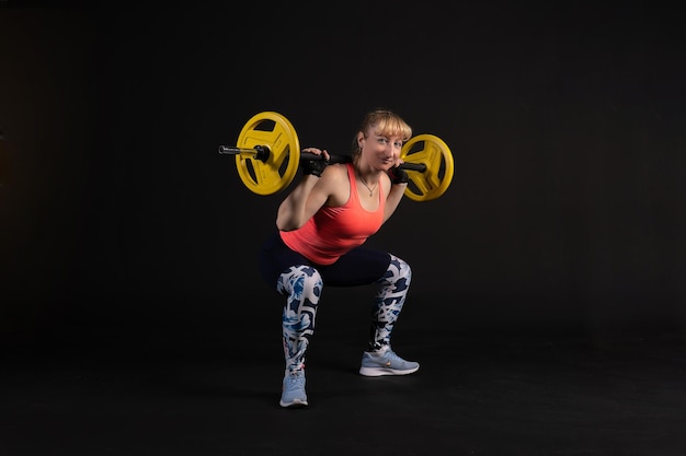 Fitness on a step platform with a barbell with dumbbells Go in for sports on a black background