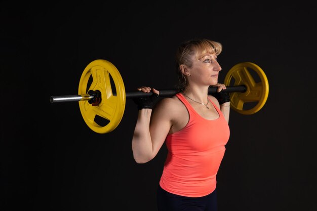 Foto fitness su una piattaforma a gradini con un bilanciere con manubri fai sport su sfondo nero