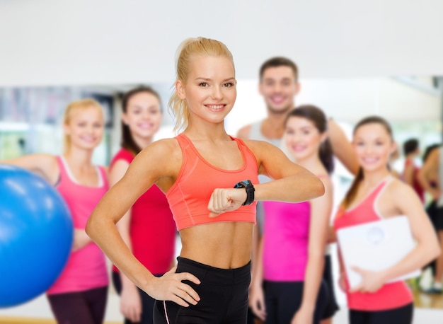 fitness, technology and exercising concept - smiling woman with heart rate monitor on hand