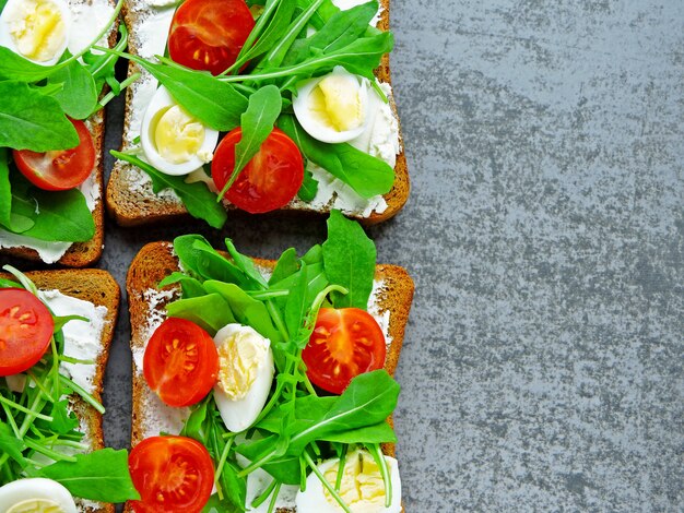 arugula, 크림 치즈, 체리 토마토 및 메추라기 계란을 가진 적당 토스트