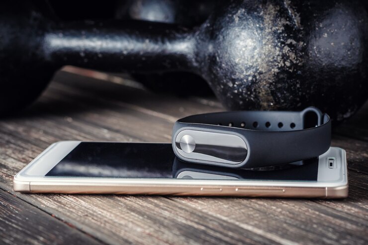 Photo fitness tracker, smartphone and iron dumbbells on a wooden background