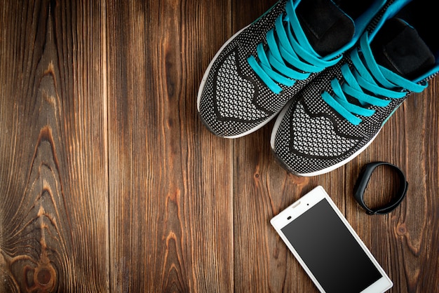 Fitness tracker and sneakers on wooden table.