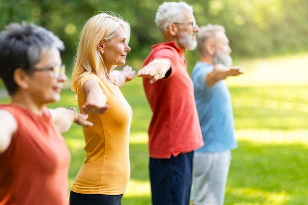 Photo fitness training group of sporty senior people exercising together outdoors