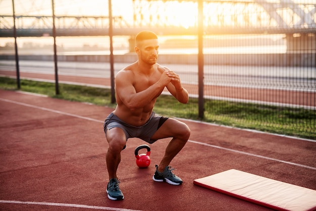 Fitness training outdoors. Handsome man working exercises in early morning with sunrise. Muscular man training outside. Sunny fitness morning.