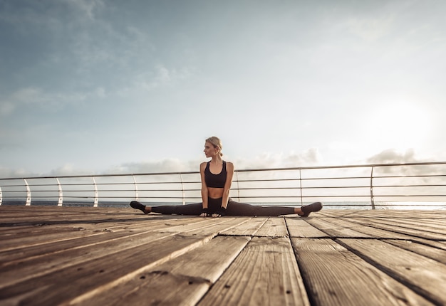 Foto fitness vrouw beoefenen van dubbele bindgaren op het strand bij zonsopgang