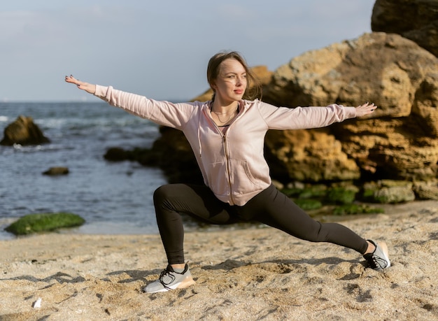 Fitness vrouw beoefenen van yoga asana houdingen op het wilde strand warrior 2