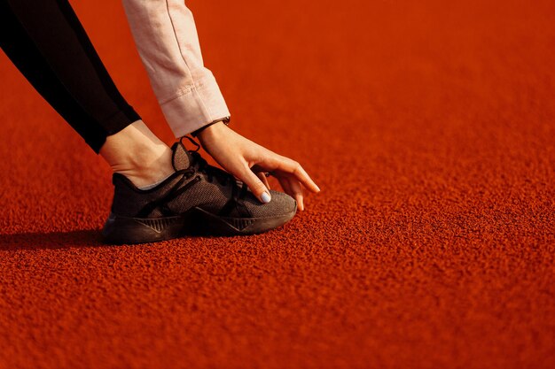 Fitness vrouw doet oefeningen voordat ze op het stadion rent Stretching en motivatie op zomertijd