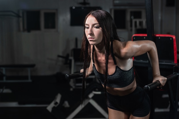 Fitness vrouw doet push-ups op ongelijke balken in crossfit gym,