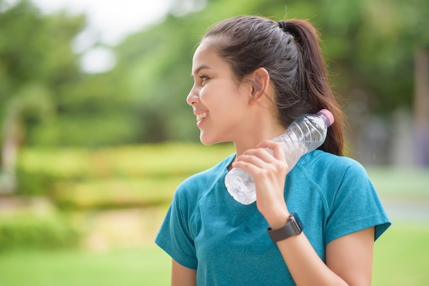 Fitness vrouw drinkwater na training in park