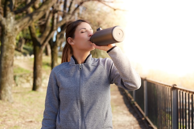 Fitness vrouw drinkwater uit een fles na training