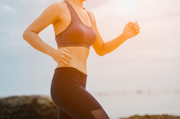 Fitness vrouw joggen bij zonsondergang op het strand.