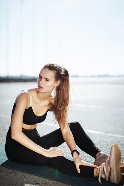 fitness vrouw ligt op straat op een yogamat