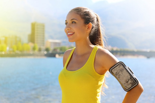 Fitness vrouw met armband voor telefoon technologie running marathon oefening joggen stretching warm in de ochtend in de stad meer.