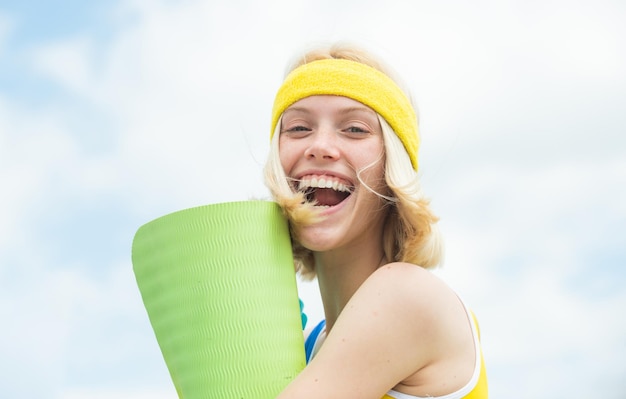 Fitness vrouw portret van lachende vrouw met oefenmat buitenshuis fit vrouw in de natuur