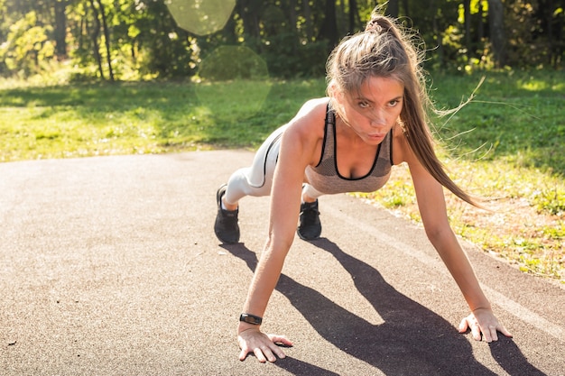 Fitness vrouw push-ups doen tijdens outdoor cross training training. Mooie jonge en fitte fitness