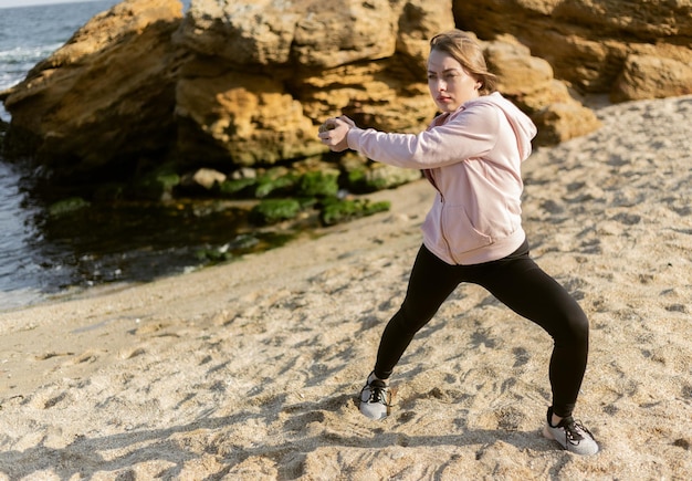 Fitness vrouw trainen met een steen op een wild strand Gezonde levensstijl fitness concept