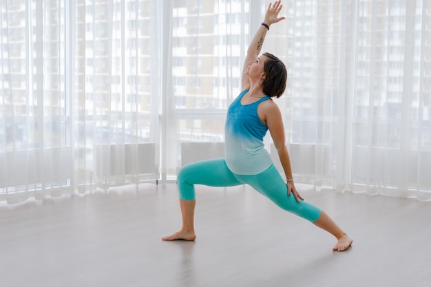 Fitness vrouw yoga strekt zich uit op de vloer in een sportschool en buigt spieren