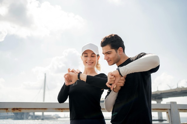 Фитнес-часы под рукой Молодая пара занимается спортом на улице, ведет здоровый образ жизни