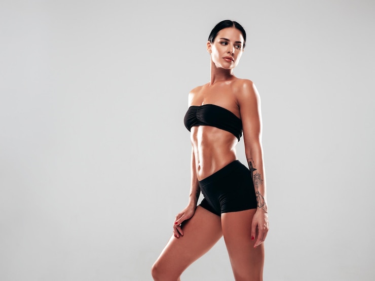 Photo fitness woman in black sports clothing stretching out before training posing on grey background