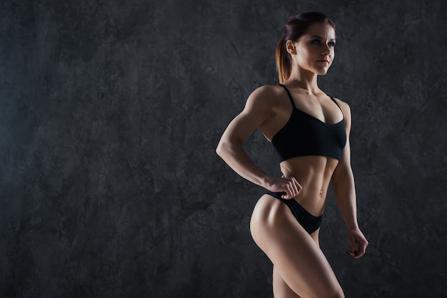 Photo fitness woman on a dark wall