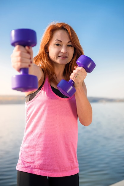 Фото Женщина фитнеса делает утреннюю тренировку с небольшими весами озера
