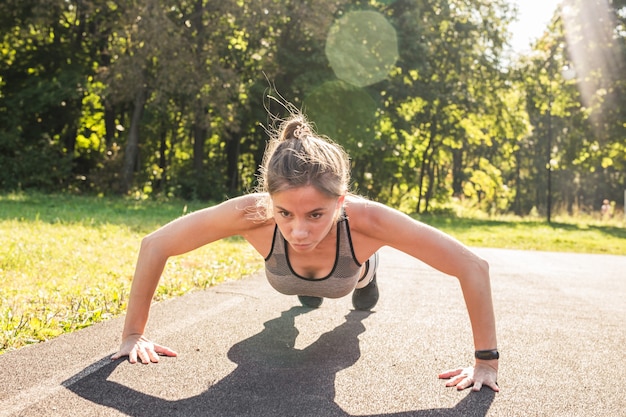 Foto donna di forma fisica che fa flessioni durante l'allenamento cross training all'aperto
