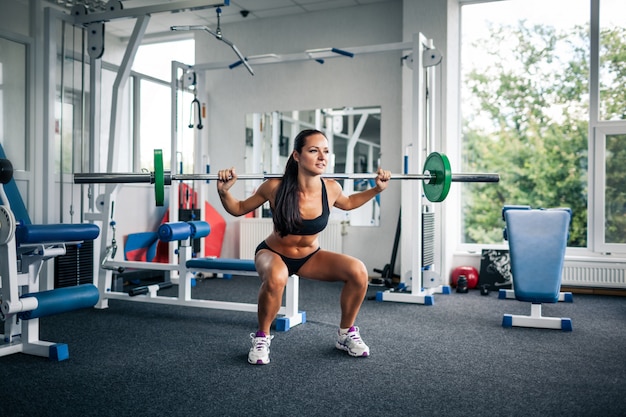 Fitness woman doing squats with barbell.