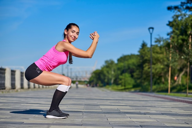 Fitness donna facendo stretching su sfondo urbano della città esercizi squat o accovacciati