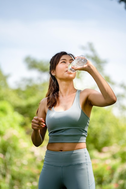 Fitness donna acqua potabile giovane donna assetata acqua potabile da una bottiglia nel parco estivo sport