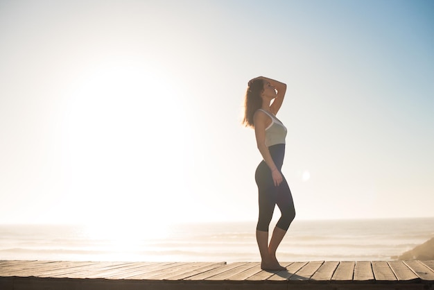 Photo fitness woman enjoying beautiful sunset on the beach