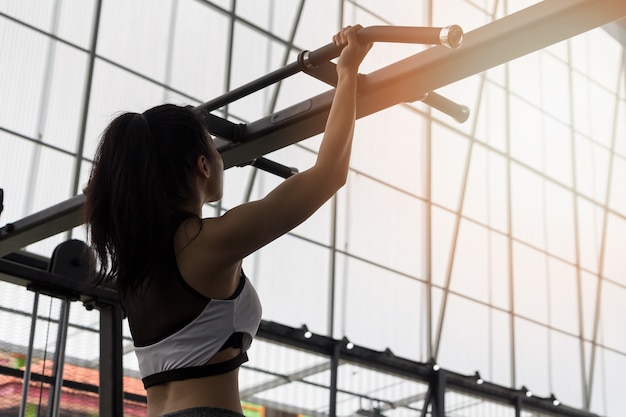 チンアップバーで運動するフィットネス女性。顎を上げるトレーニングを行っている運動選手。