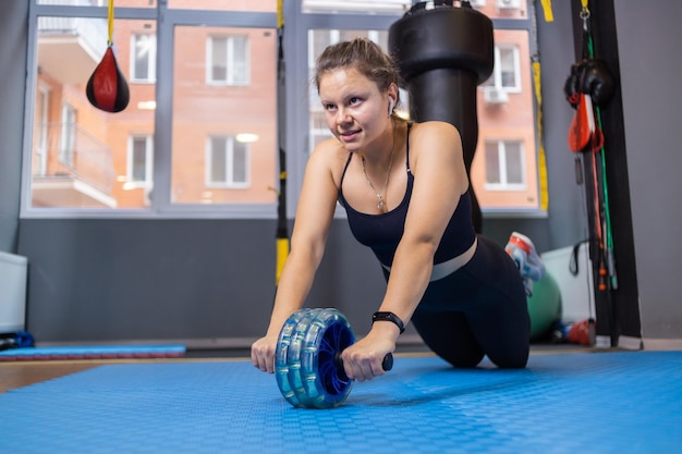 Fitness woman exercising with abs wheel in the room Healthy lifestyle