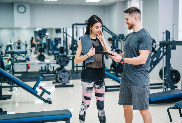 Fitness woman exercising with fitness trainer in gym. 