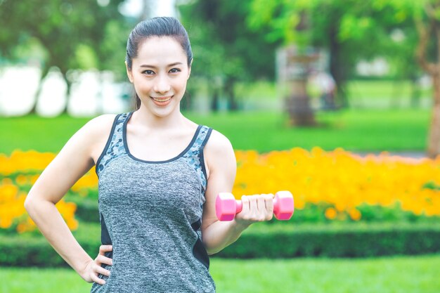 Fitness woman lifting small dumbbells in the park morning