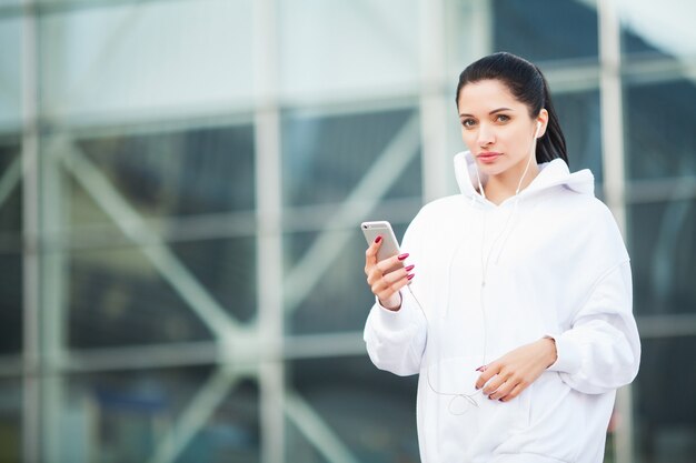 Фитнес. Музыка женщины слушая на телефоне пока работающ Outdoors - концепция спорта и здорового образа жизни