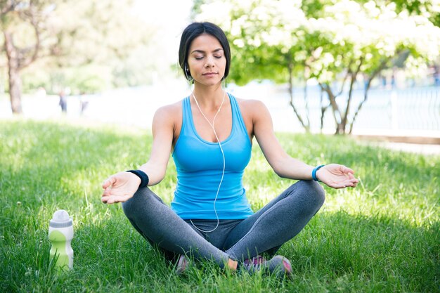 緑の芝生で瞑想するフィットネス女性