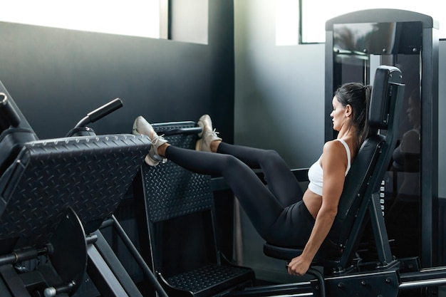 Фитнес-женщина выполняет упражнения на тренажере для ног