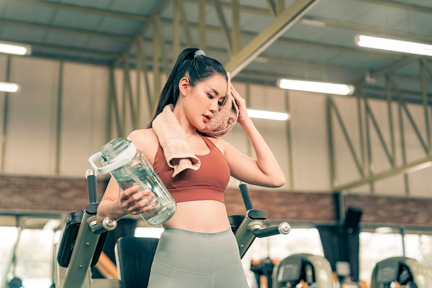 Фото Фитнес-женщина отдыхает от упражнений в тренажерном зале и пьет воду из бутылки