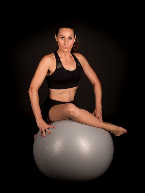 Fitness woman sitting on gray fitball ball