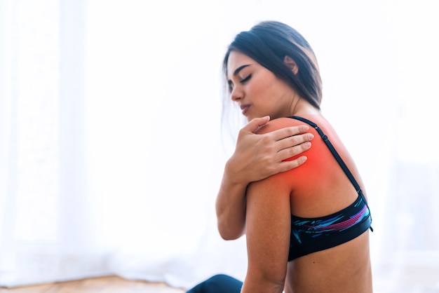 Donna di forma fisica che soffre di infortunio alla spalla durante l'allenamento. copia lo sfondo dello spazio.