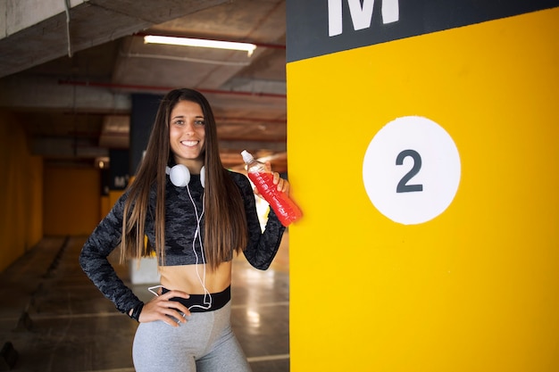 Fitness woman taking a break and holding energy drink on training.