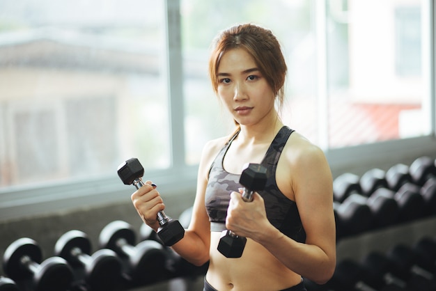 Fitness woman in training exercises with dumbbells.