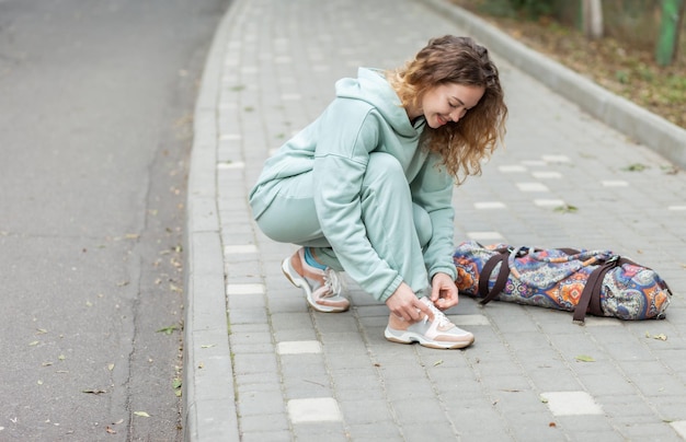 Photo fitness woman tying shoelaces outdoors