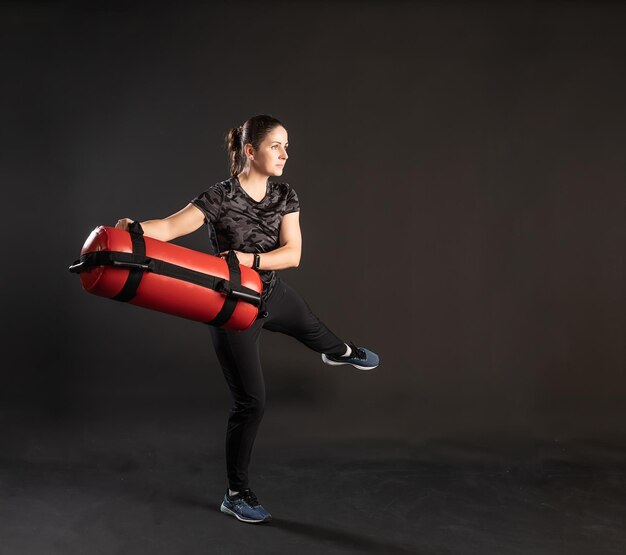 Photo fitness woman with aqua bag sideways leg moves engaged in sports on a black background