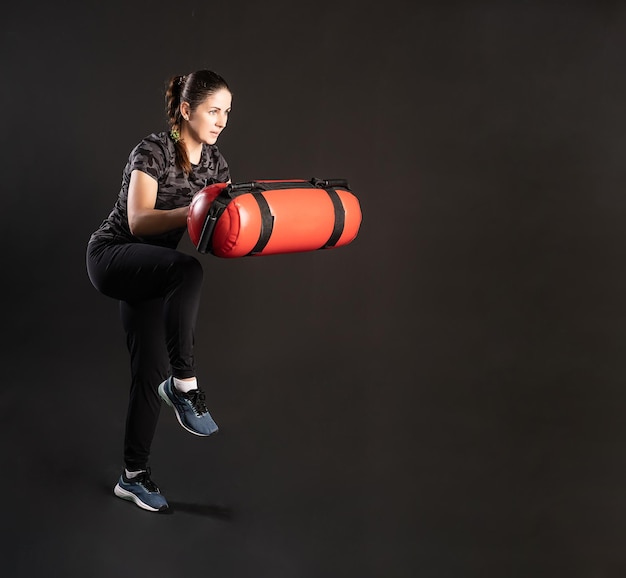 Photo fitness woman with aqua bag stretches her leg sports on a black background smiling with gentle lips