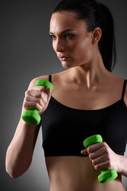 Fitness woman working out with green dumbbell